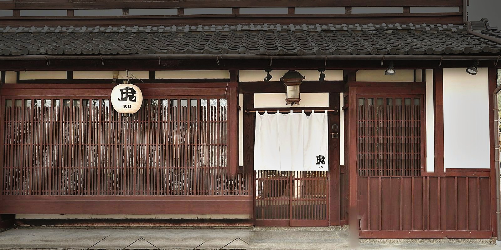 「虎 KO」の提灯と白い暖簾がかかる、百年町屋の正面