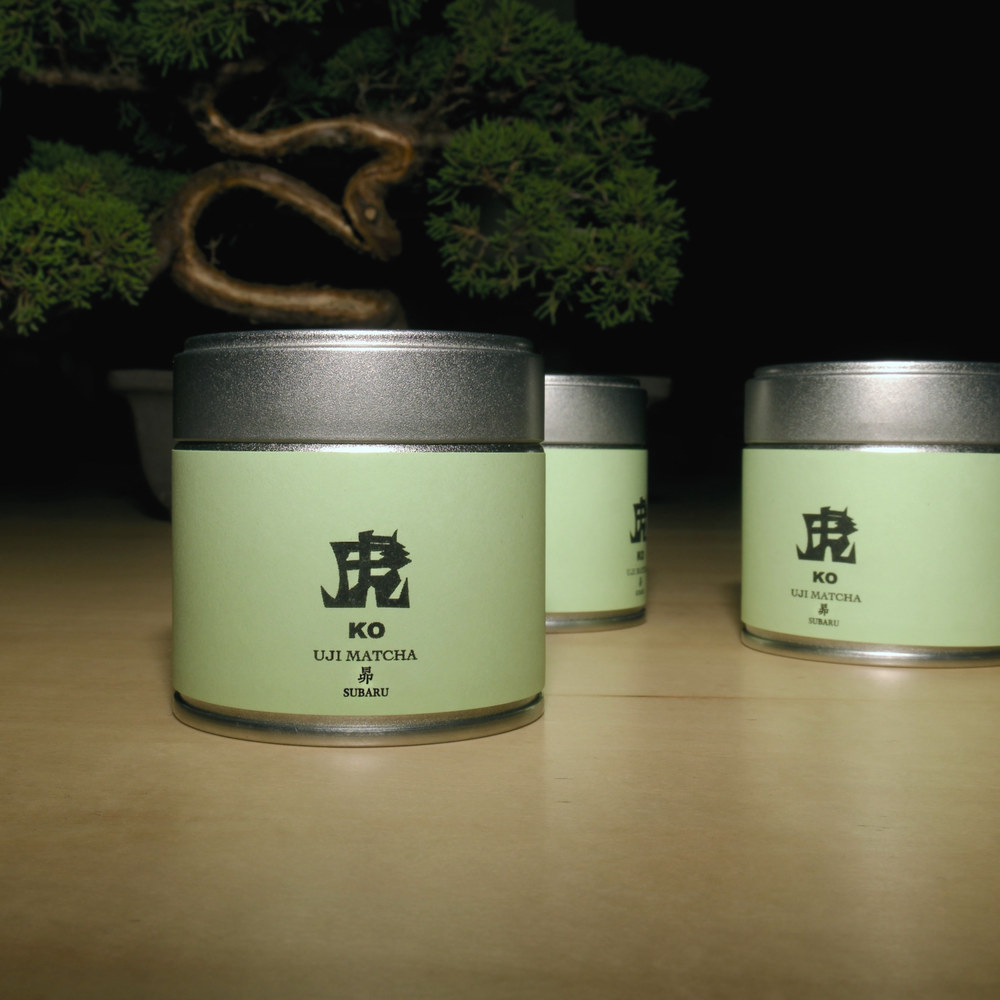 木地の上に並ぶ、宇治抹茶「昴」の缶
