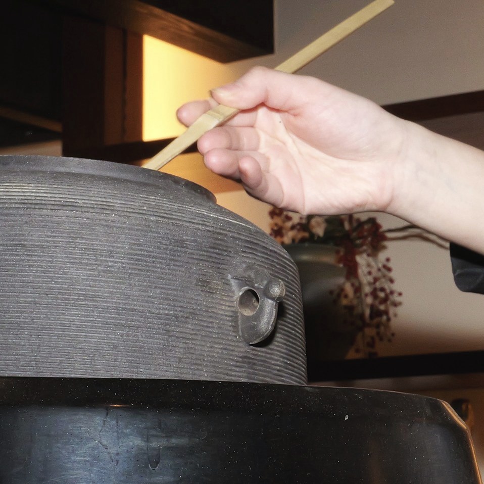 大きな茶釜から柄杓で湯を汲む手元