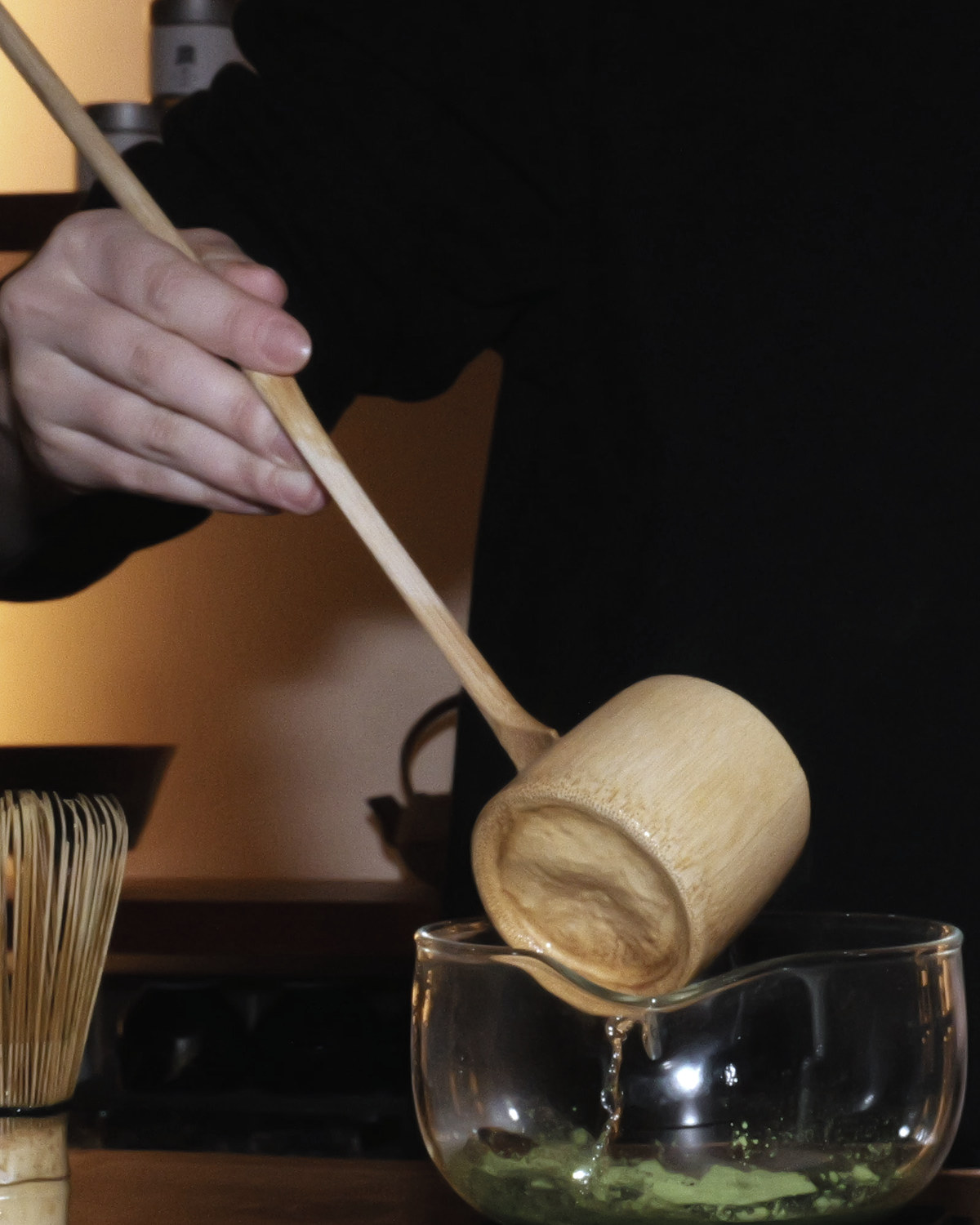 柄杓から湯を注ぐ手元。かたわらに茶筅が立つ